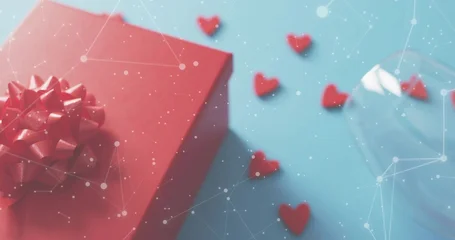 Fotobehang Vlees Red gift box sitting on blue tabletop, showing heart confetti, tilted stemmed glass, dotted overlay  © vectorfusionart