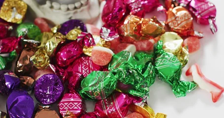 Fotobehang Vlees Displaying pile of colorful foil-wrapped and twist-wrapped candies with gummy pieces on white plate  © vectorfusionart