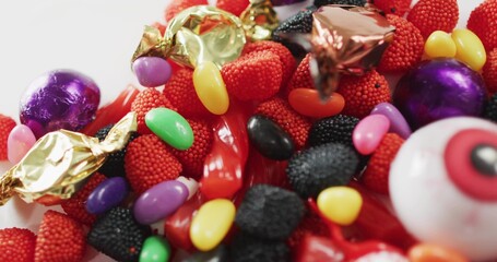 Displaying candy pile on white tabletop, showing eyeball candy, red gummies and foil chocolates © vectorfusionart