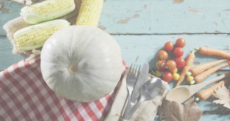 Showing white pumpkin sitting on worn blue table, with gingham, corn, tomatoes, fork, spoon © vectorfusionart
