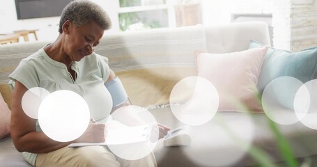 Recording woman in pale green blouse with cuff on sofa at home, noting monitor reading
