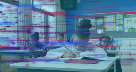 Writing child student in white long-sleeve top leaning over front desk in classroom, with notebook