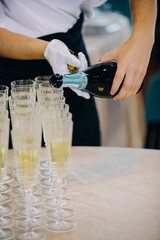 Server opening sparkling wine bottle at celebration event