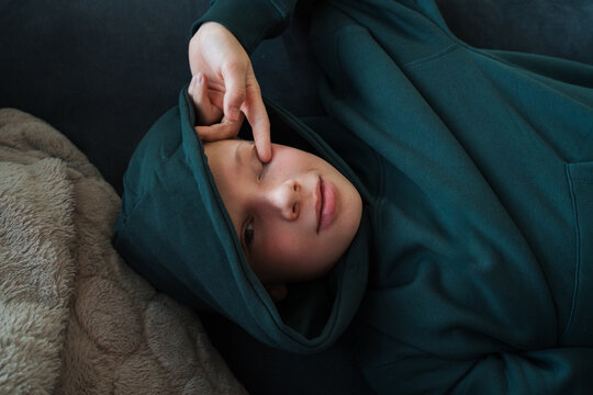 tired teenage boy laying on the sofa looking into the camera