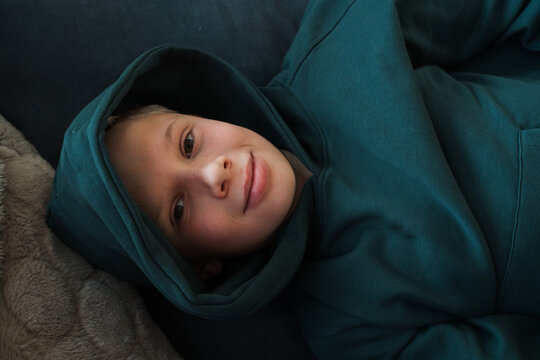 teenage boy laying down on the sofa looking at the camera