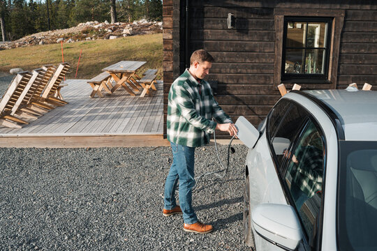 man plugging in his electric car at his cabin