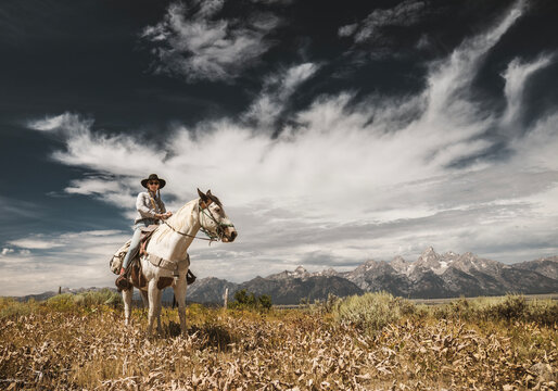 Woman rides horse with Tetons in background, Wyoming