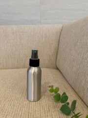 Silver Spray Bottle on Beige Sofa with Green Leaf
