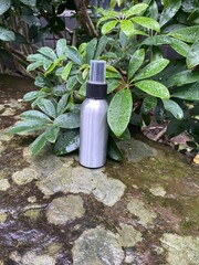 Spray Bottle on Wet Stone with Raindrops on Leaves