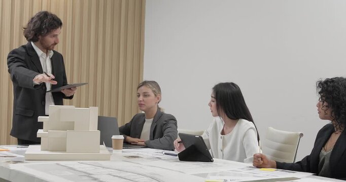 Architects and designers collaborate on an eco-friendly building project, discuss sustainable design elements and 3D architectural model. Planning energy-efficient solutions to reduce carbon footprint