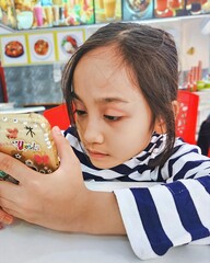 Malaysia, Bangi - September 7, 2024 Little girl using mobile phone at the restaurant.