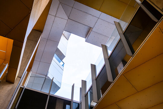 An intriguing perspective capturing a vivid architectural space, showcasing concrete and glass structures converging towards an open sky, symbolizing freedom and innovation.