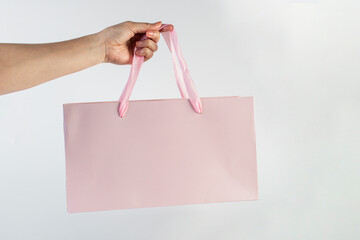 Pink paper shopping bag in hand on white background.
