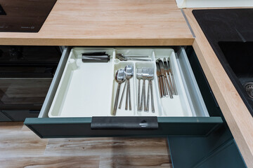 organized utensil and drawer layout, apartment resident reviews cutlery and storage arrangements, home occupant examines utensils and compartment setup to ensure efficient kitchen storage