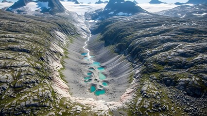 Aerial view of a serene mountain valley with turquoise lakes and snow-capped peaks in the background.