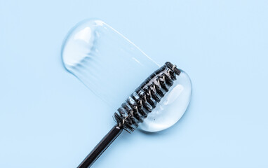 Close-up of transparent eyelash eyebrow gel serum, smooth and shiny texture, blue background