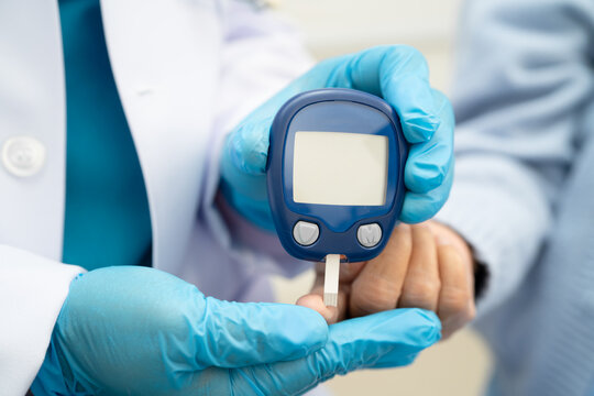 Asian doctor using digital glucose meter for check sample blood sugar level to treatment diabetes.