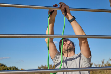 Fototapeta premium Man attaching resistance band to metal bars before workout.