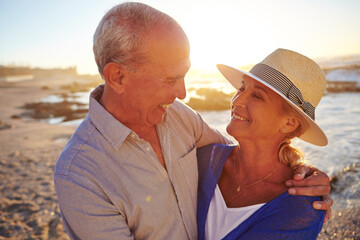 Sunset, hug and senior couple by beach on summer vacation, getaway or weekend trip together. Happy, love and old man with woman for embracing with care, connection or bonding by ocean on holiday.