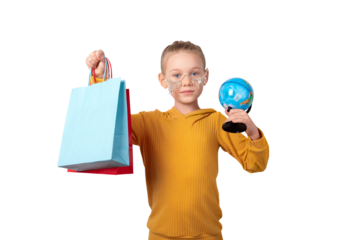 Smiling girl in yellow sweater holding colorful shopping bags and a globe, standing against a transparent background. Concept of global shopping and childhood curiosity.