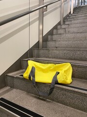Yellow Duffel Bag Left on Staircase in Urban Station