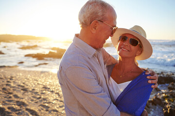 Smile, hug and senior couple by beach on summer vacation, getaway or weekend trip together. Sunset, love and old man with woman for embracing with care, connection or bonding by ocean on holiday.