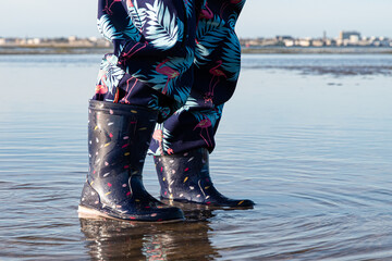Enfant marchant en bottes dans l'eau ) marée basse