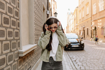 Obraz premium A woman walks and listens to headphones with her hands on them