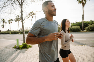 A male athlete runs next to a female athlete who is laughing