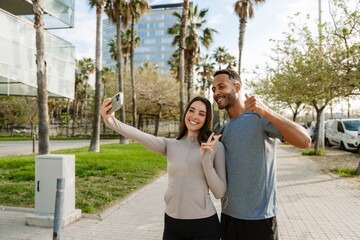 Male and female athletes gesturing and smiling while standing and posing in front of a phone she is holding