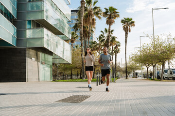 Female athlete laughing while jogging with male athlete