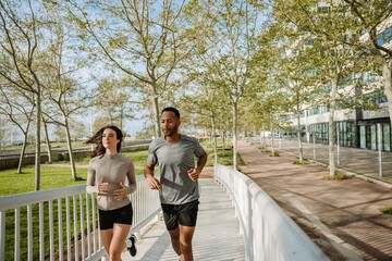 Male and female athletes running focused up the bridge