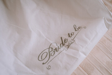 Elegant white fabric with delicate script reading "Bride to be," showcasing a soft texture and romantic ambiance, perfect for wedding celebrations and bridal events