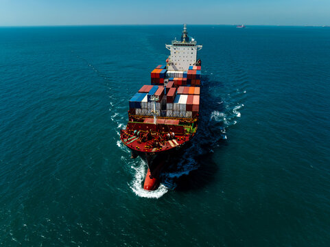 Aerial high angle front view of cargo ship sailing with symmetrical composition