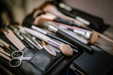 Collection of various makeup brushes and tools arranged neatly in a black leather case, showcasing the artistry and precision involved in beauty and cosmetic application