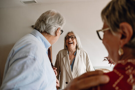 Woman laughing and listening to her male friend standing next to her female friend - Powered by Adobe