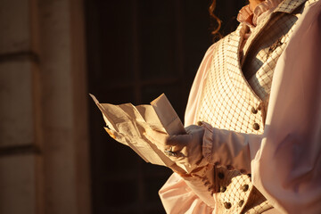 Fototapeta premium A woman in a vintage dress reads a letter near the columns of an ancient cathedral.