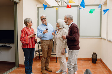 Group of four friends laughing and smiling while holding glasses and standing