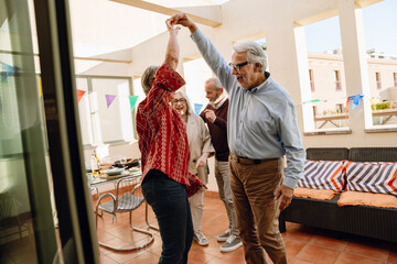 A woman spins and holds the hand of a man who is talking while two of their friends are talking nearby
