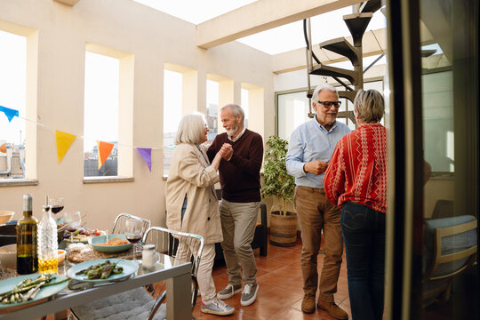 A group of four friends dance in pairs and smile while two of them hold hands