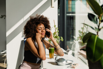 Woman talking on the phone with closed eyes while sitting at a table