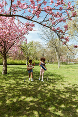Fototapeta premium Two female friends walking on grass and carrying mats while smiling and talking