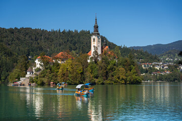 Fototapeta premium Pilgrimage Church of the Assumption of Mary (Bled Island Church). Bled Island. Stunning Panoramic View of Lake Bled with Iconic Island and Castle, Slovenia. Romantic spot. Typical Bled boat (Pletna).