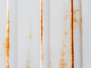 Close-up of rusty white metal sheet with vertical lines and aged surface texture