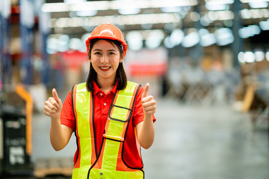 A woman wearing a safety vest and a hard hat is giving a thumbs up