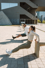 Woman and man doing triceps exercises on stone chairs