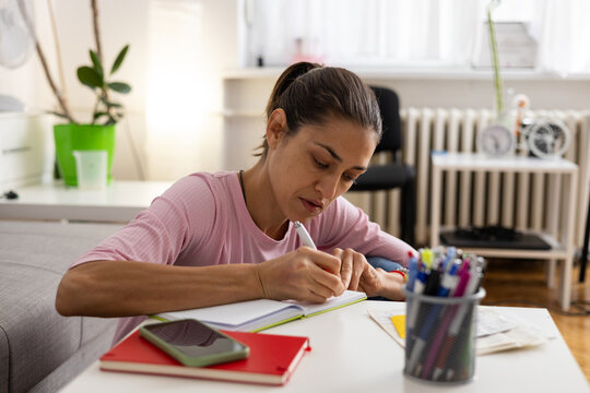 Woman writing in a notebook, concentrating on her planning