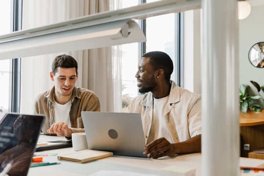Two male workers laughing and talking while sitting at a table
