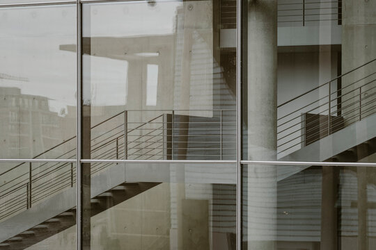 An abstract image featuring a staircase viewed through glass panels, emphasizing the interplay of lines and reflections, creating a captivating modern architectural composition.