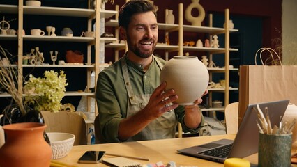 Happy glad Caucasian artisan man male guy businessman small business owner crock potter looking at porcelain vase ceramic crockery pot clay creation admiring perfect quality excellence inside workshop
